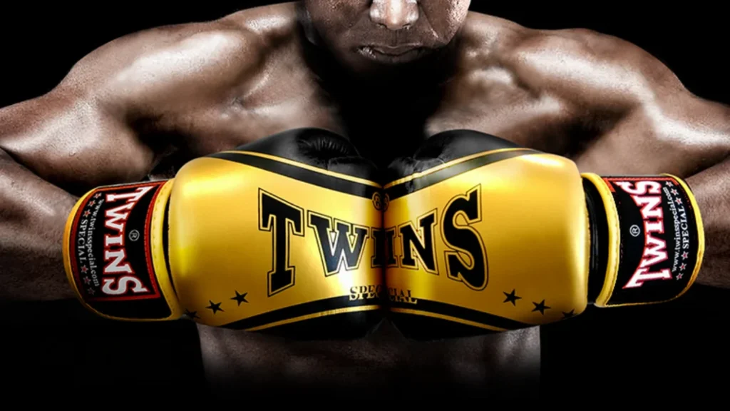 Zbliżenie na żółto-czarne rękawice bokserskie Twins Special, symbolizujące ochronę dłoni i rolę bandaży bokserskich w sporcie.